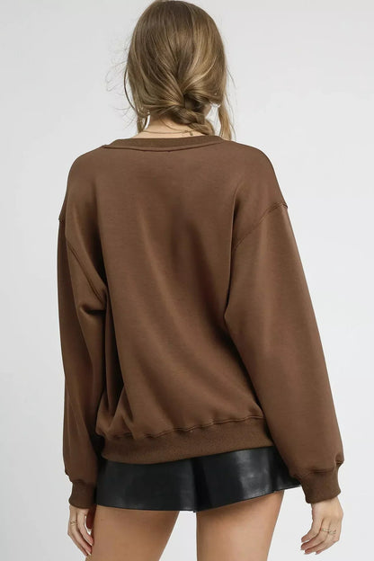 Woman wearing an oversized mocha brown sweatshirt and black faux leather shorts, back view