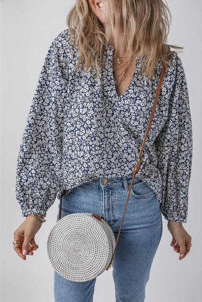 Woman wearing a blue floral blouse with balloon sleeves, light jeans, and a round woven crossbody bag