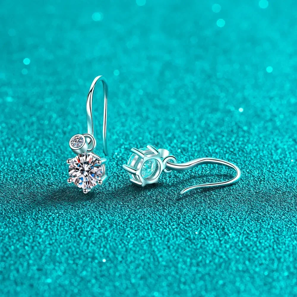 Silver drop earrings with round clear gemstones on teal glitter background