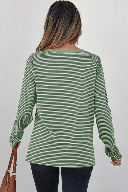 Woman wearing a green and white striped long sleeve top with dark jeans, back view