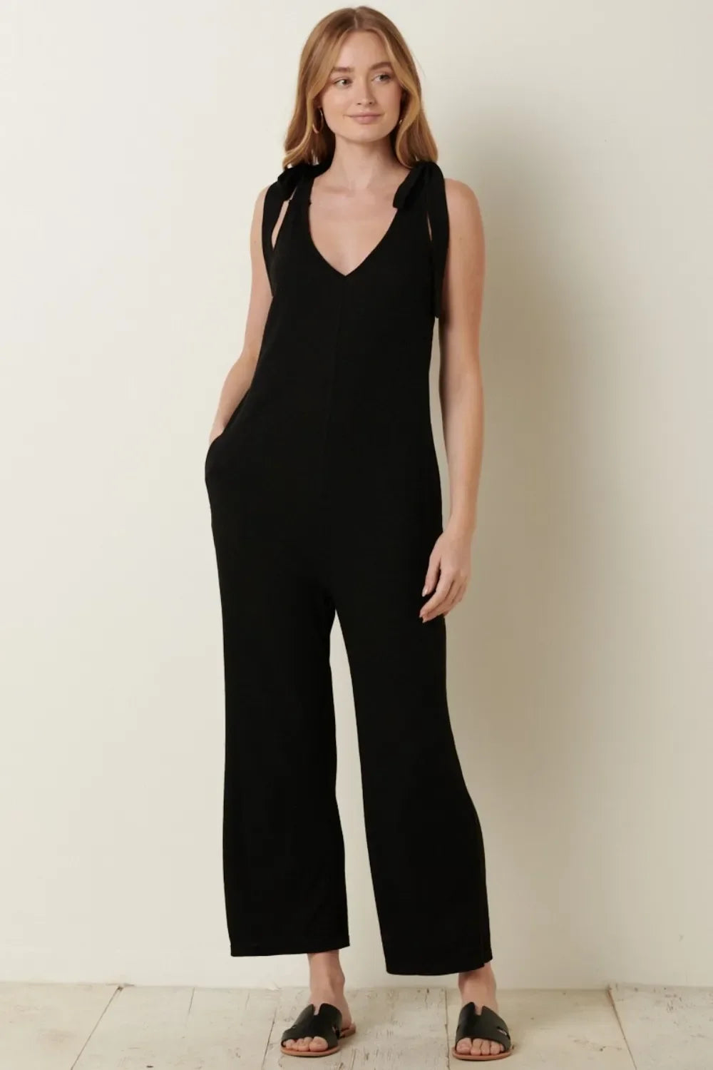 Woman wearing a black sleeveless jumpsuit with tie straps and wide-leg pants