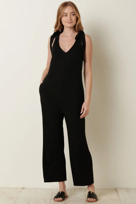 Woman wearing a black sleeveless jumpsuit with tie straps and wide-leg pants