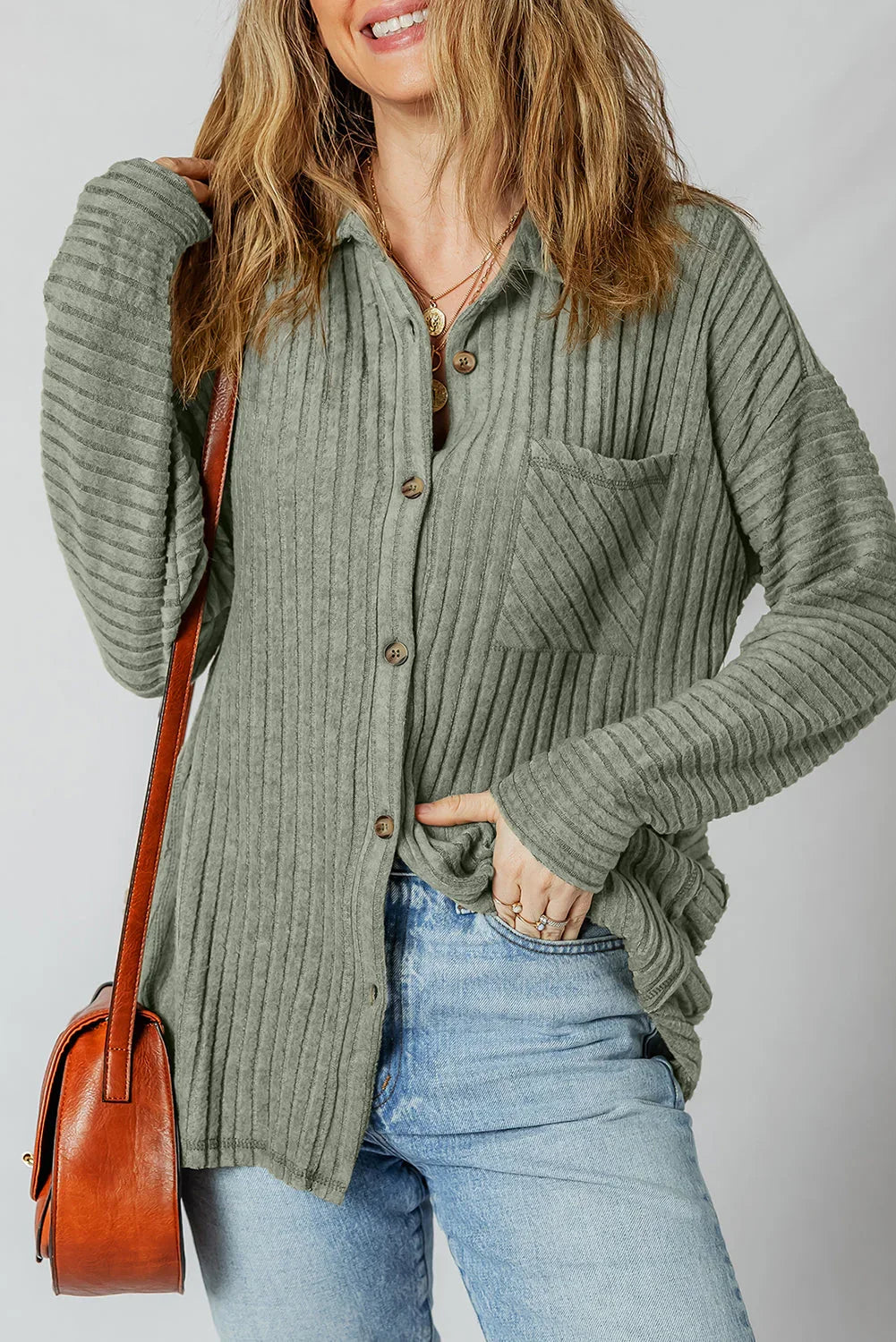 Woman wearing a ribbed sage green button-up shirt with jeans and a brown shoulder bag