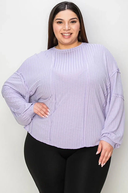 Woman wearing a long sleeve, light purple ribbed blouse with a relaxed fit and black pants