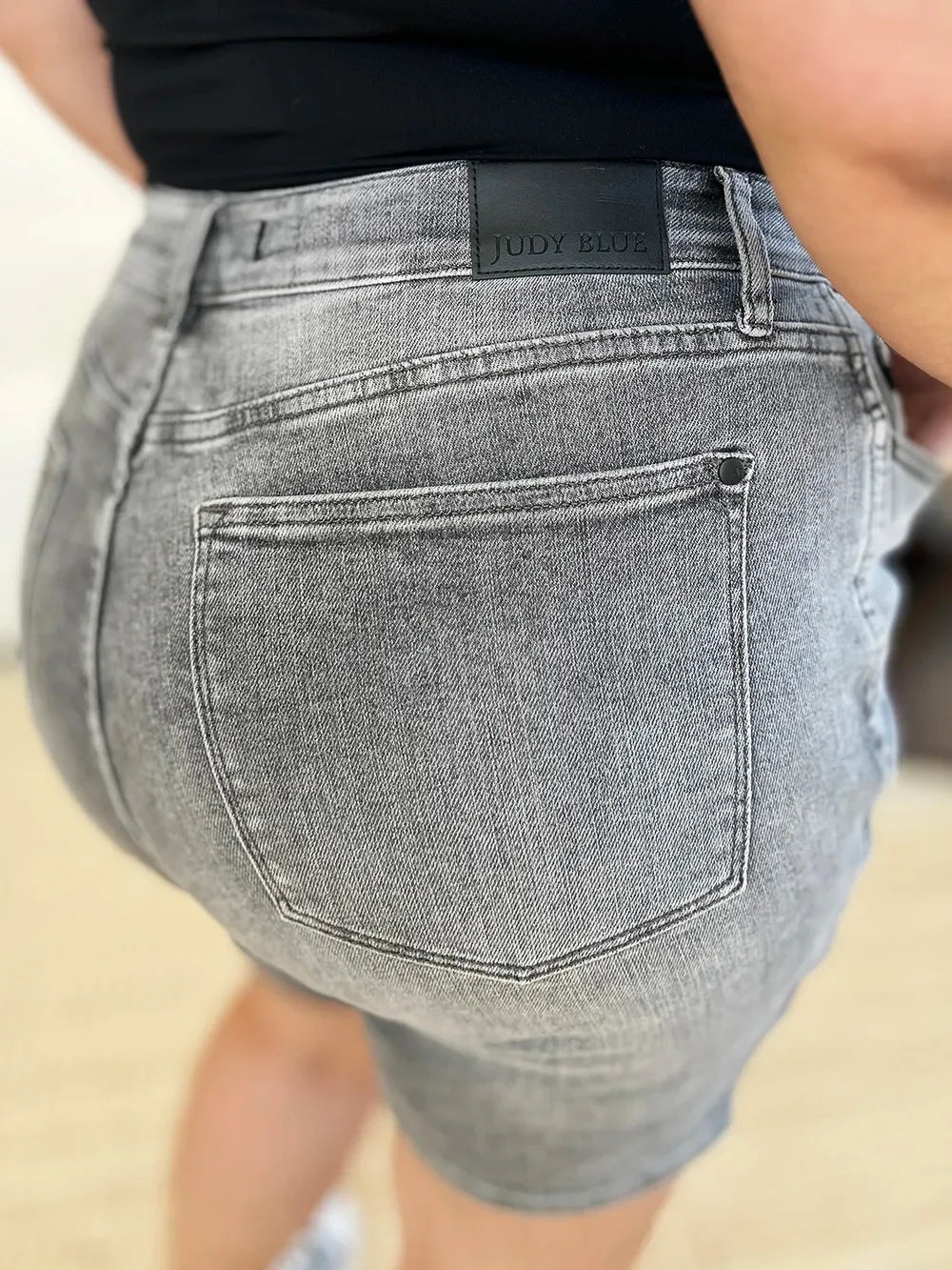 Close-up of woman wearing high-waisted gray denim shorts with back pocket detail