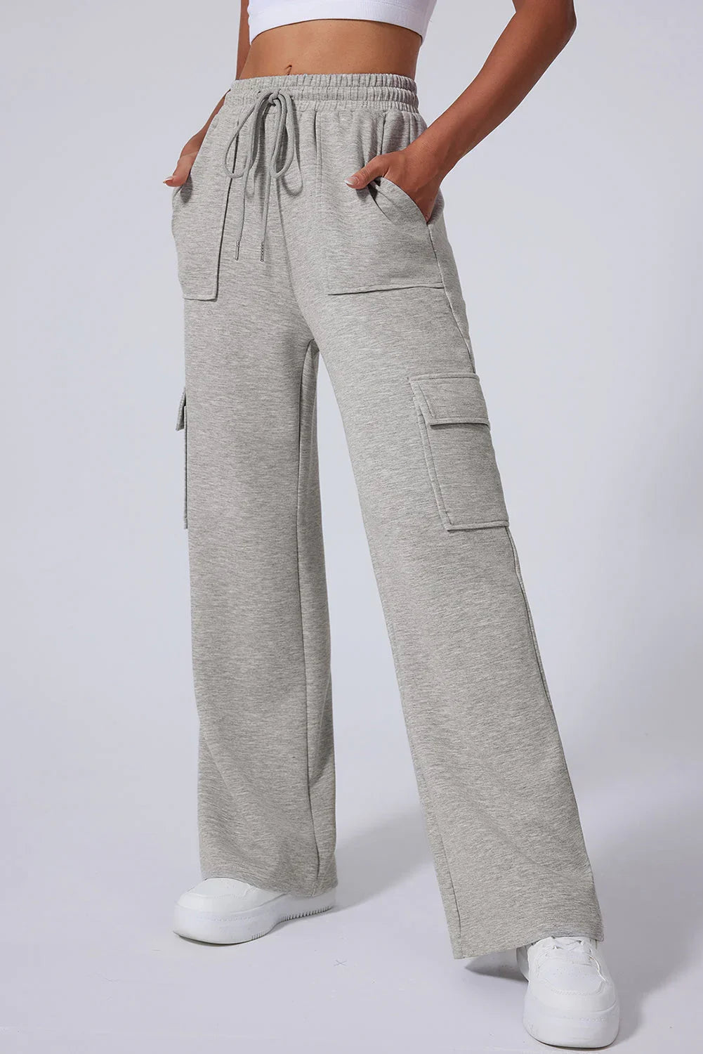 Woman wearing light grey wide-leg cargo sweatpants with drawstring and pockets