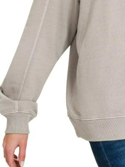 Close-up of beige long-sleeve relaxed sweatshirt with ribbed cuffs and hem, paired with jeans