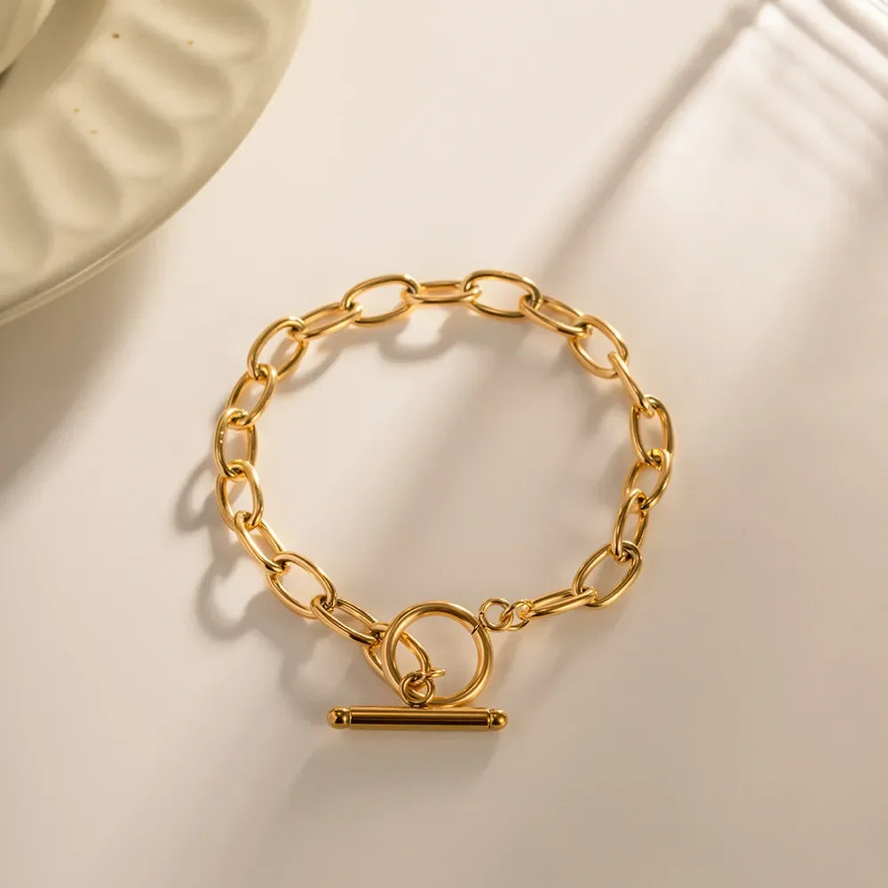 Gold chain link bracelet with toggle clasp on neutral background