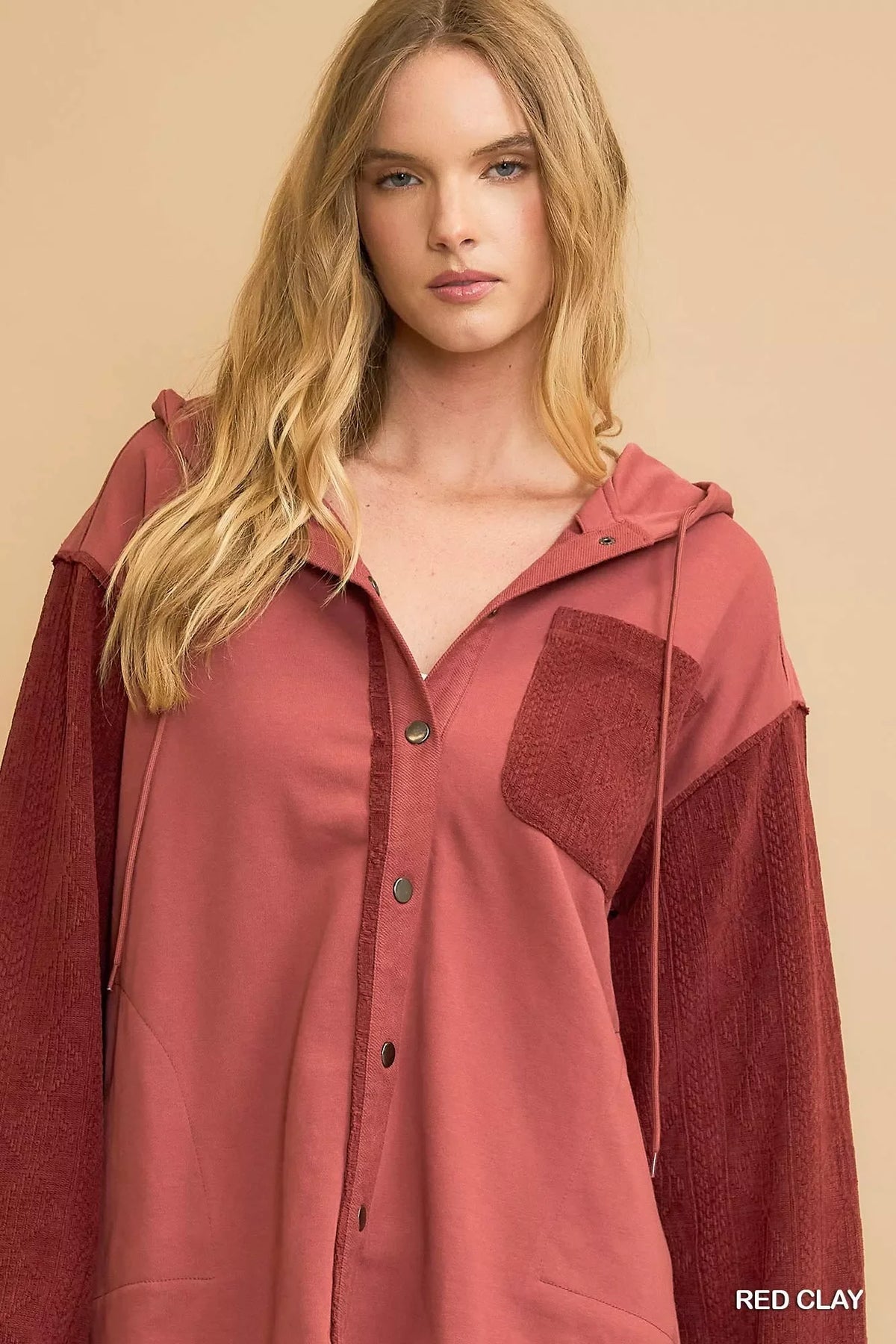 Woman wearing a red clay button-up hooded shirt with textured sleeves and front pocket