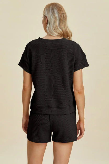 Woman wearing black textured short-sleeve top and shorts set, back view