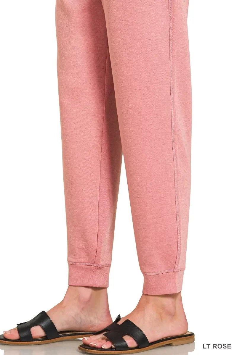 Light rose jogger pants with cuffed ankles, styled with black slide sandals.