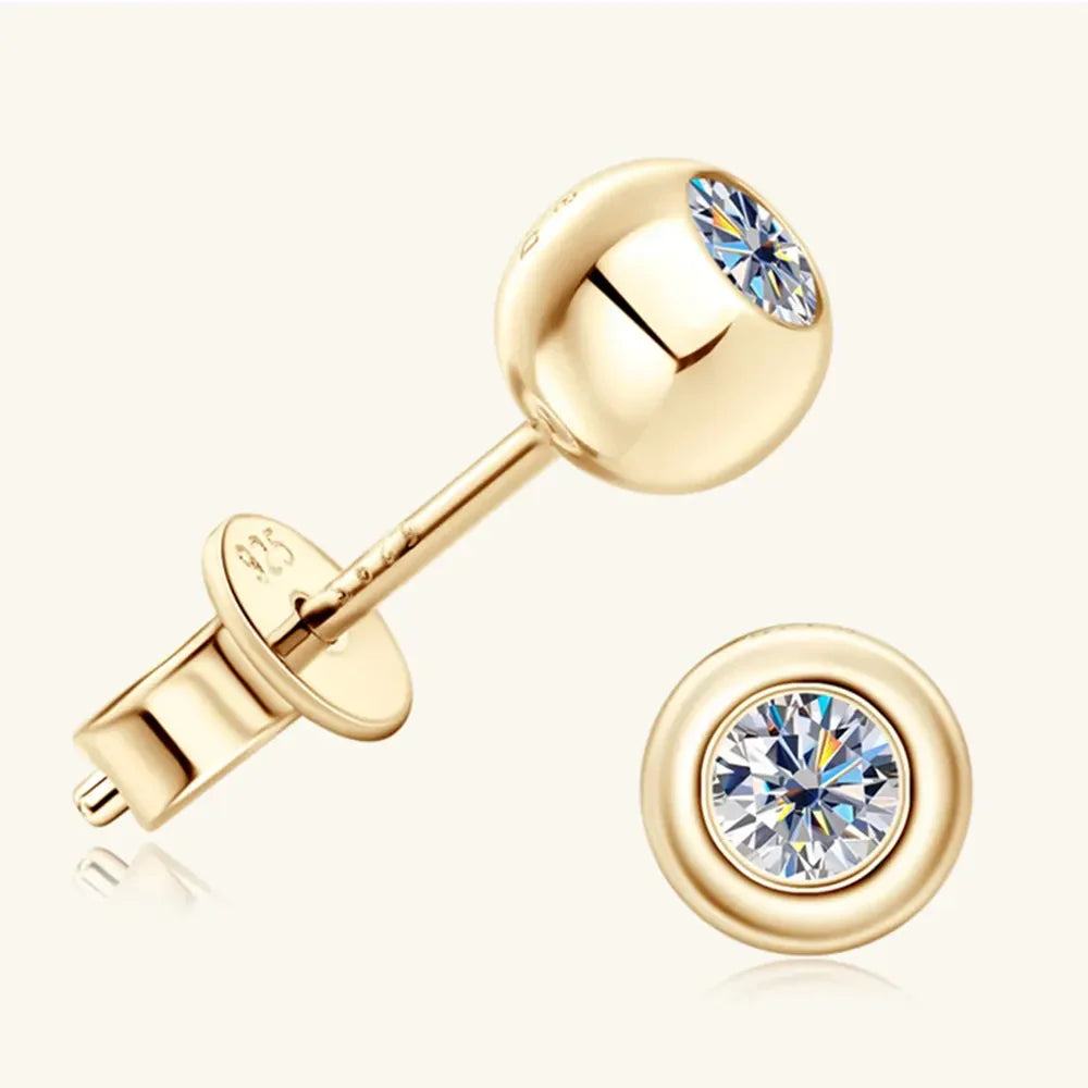Gold stud earrings with round clear gemstone center on light background.