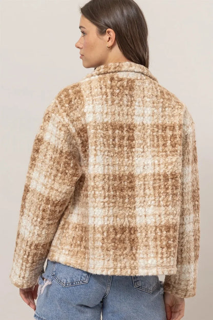 Woman wearing a beige and white plaid textured jacket with relaxed fit, paired with blue jeans.