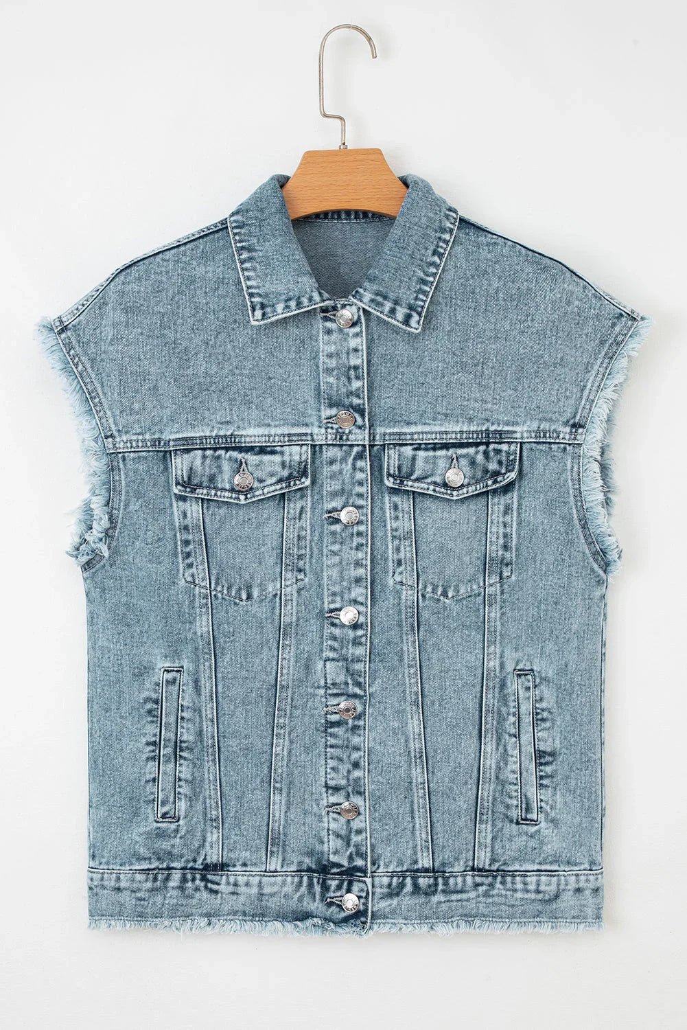 Sleeveless light wash denim vest with frayed edges and button front on hanger