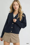 Woman wearing a navy button-up cardigan and beige high-waist shorts against a plain background
