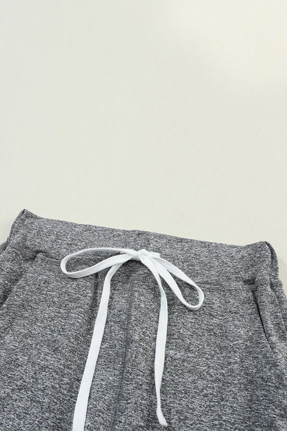 Close-up of heather grey knit joggers with white drawstring on a neutral background