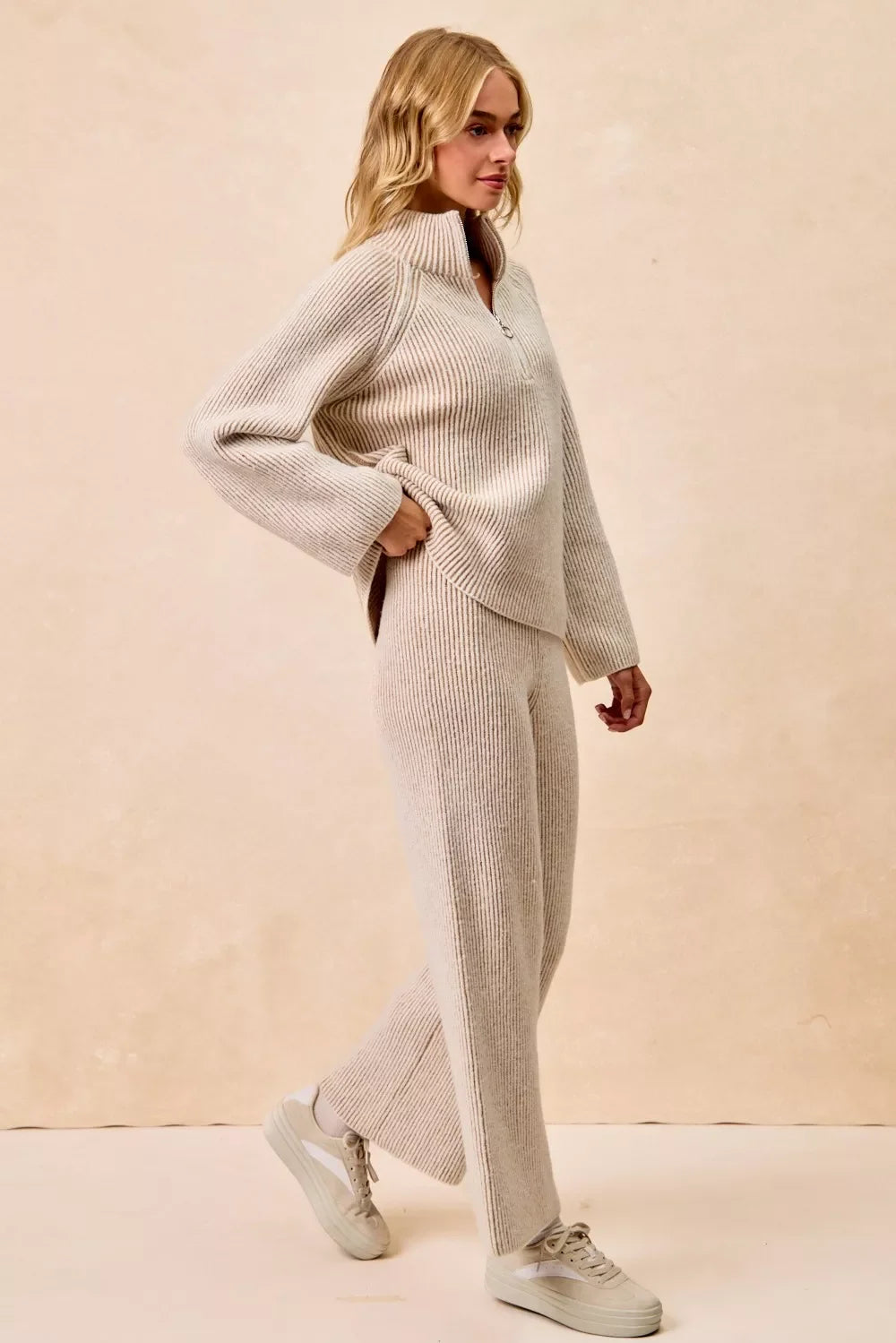 Woman wearing a beige ribbed knit sweater and matching pants set with casual sneakers