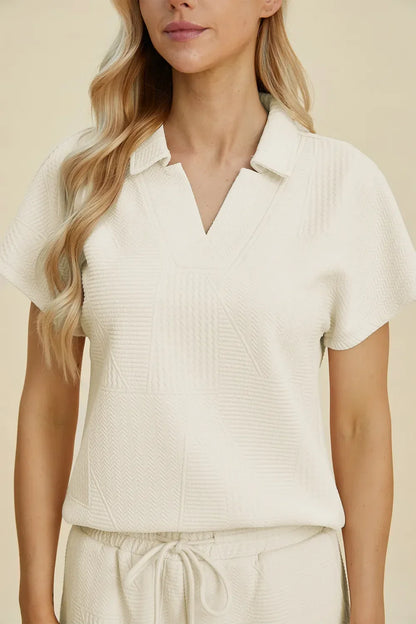 Woman wearing a textured ivory short sleeve collared top and matching drawstring shorts