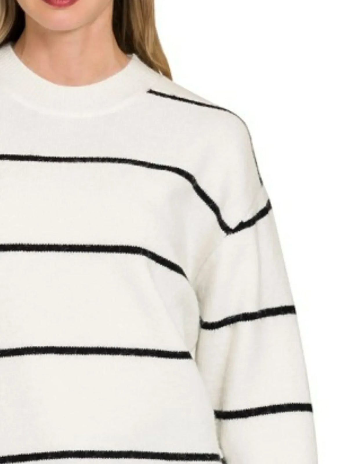 Woman wearing a white sweater with black horizontal stripes and a crew neckline