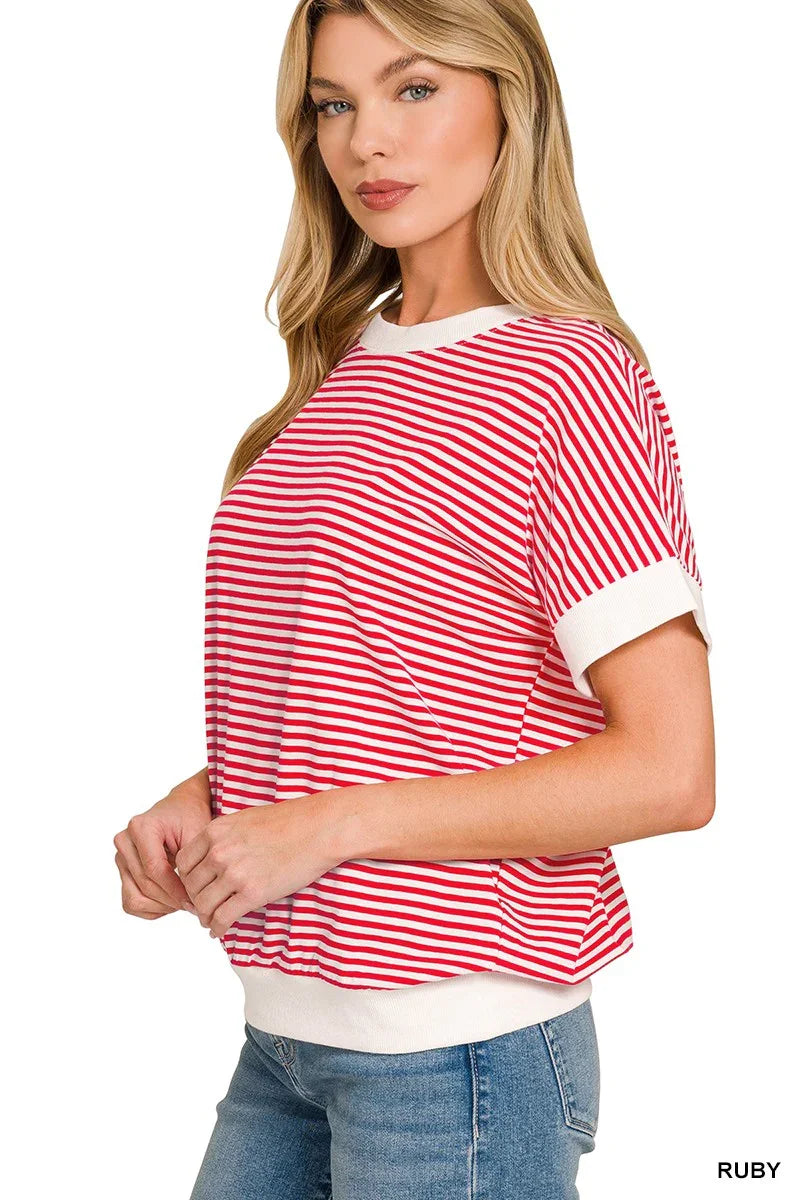 Woman wearing a relaxed red and white striped short sleeve top with white trim and blue jeans.