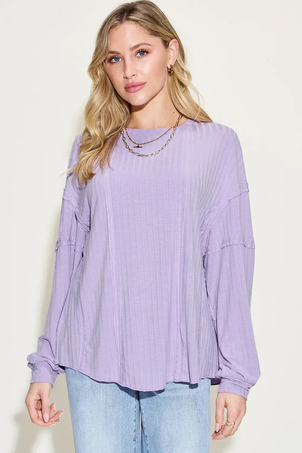 Woman wearing a relaxed lilac long-sleeve blouse with textured fabric and light blue jeans