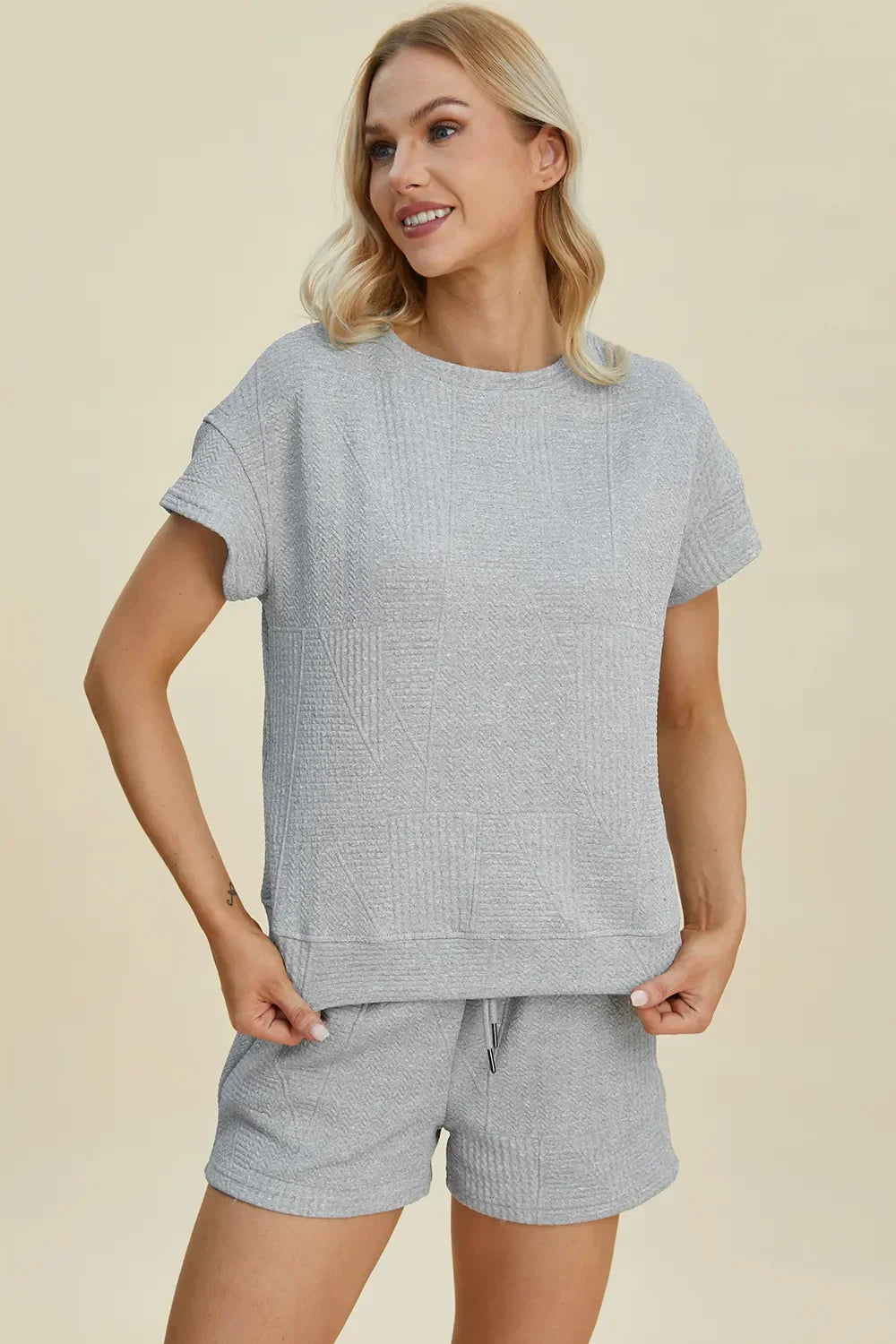 Woman wearing light grey textured short sleeve lounge set with matching shorts