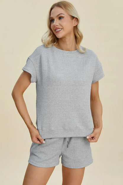 Woman wearing light grey textured short sleeve lounge set with matching shorts