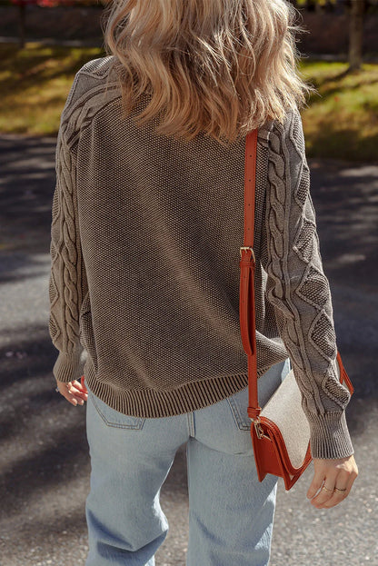 Woman in chunky knit taupe sweater and light denim jeans, crossbody bag outdoors