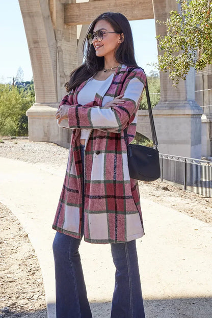 Woman outdoors wearing a pink plaid long coat, white top, flared jeans, and sunglasses