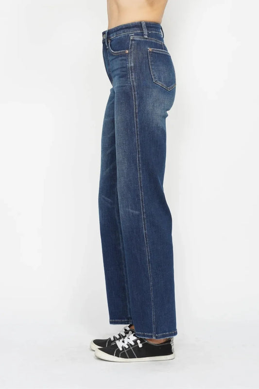 Side view of woman wearing high-waisted straight-leg blue jeans and black sneakers