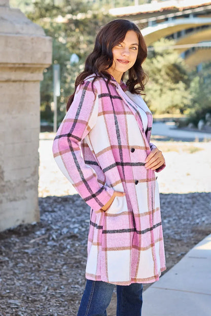 Woman wearing a pink and white plaid long coat with double-breasted buttons outdoors