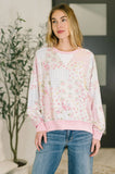 Woman wearing a pastel floral patchwork top with ribbed trim and blue jeans indoors