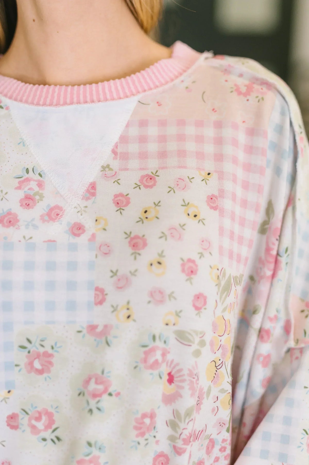 Close-up of a women's patchwork top with pastel floral and gingham patterns and pink collar