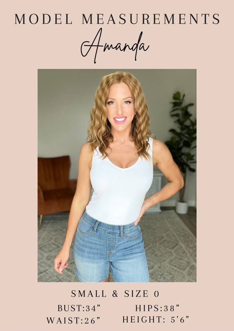 Woman wearing a white tank top and blue jeans with model measurements displayed.