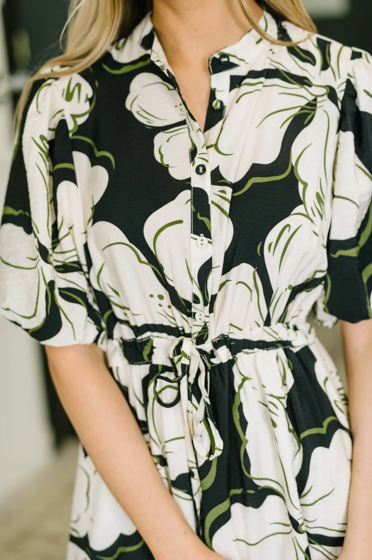 Woman wearing a puff sleeve midi dress with abstract black and green floral print