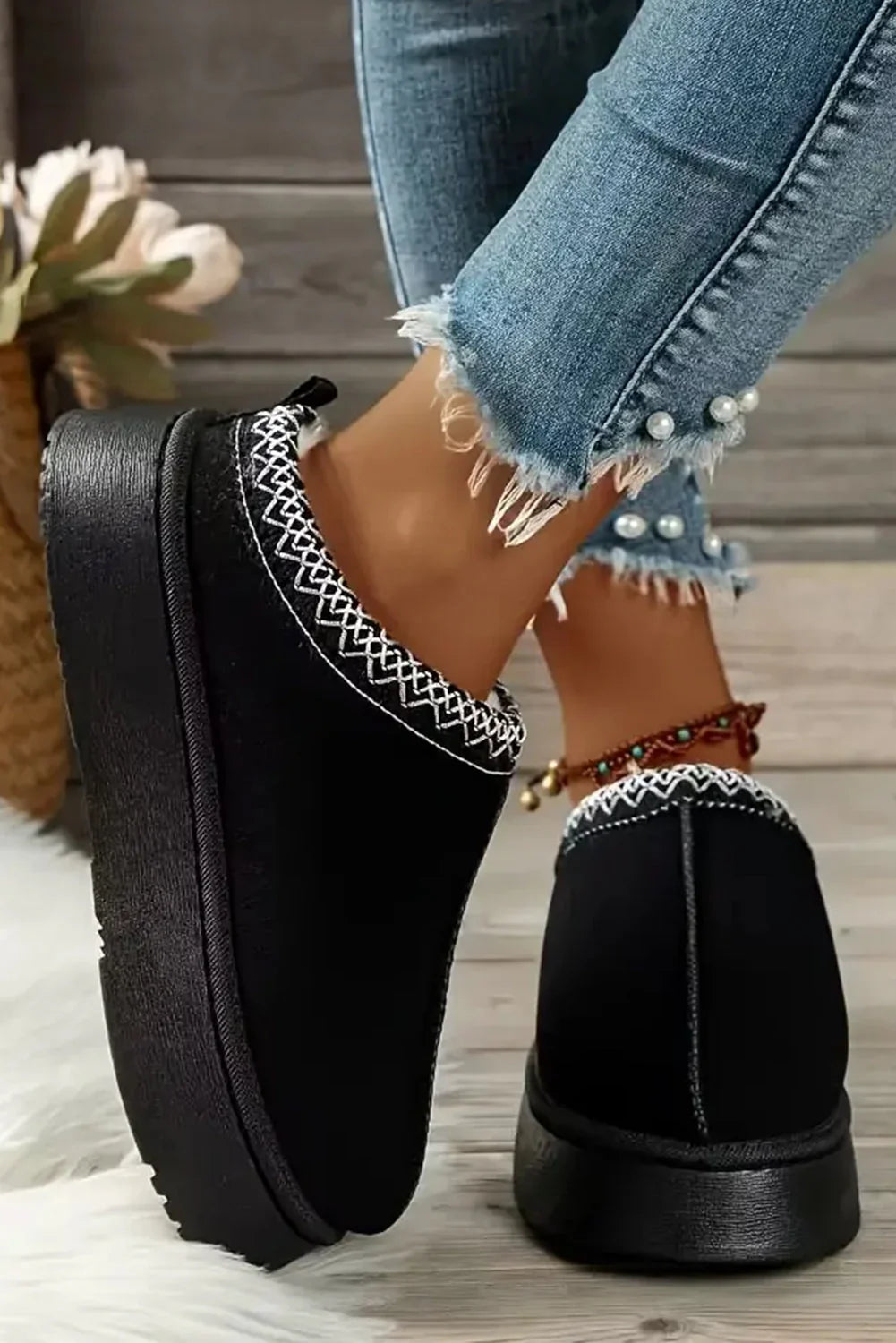 Black slip-on mule shoes with white stitched trim, paired with frayed hem pearl jeans
