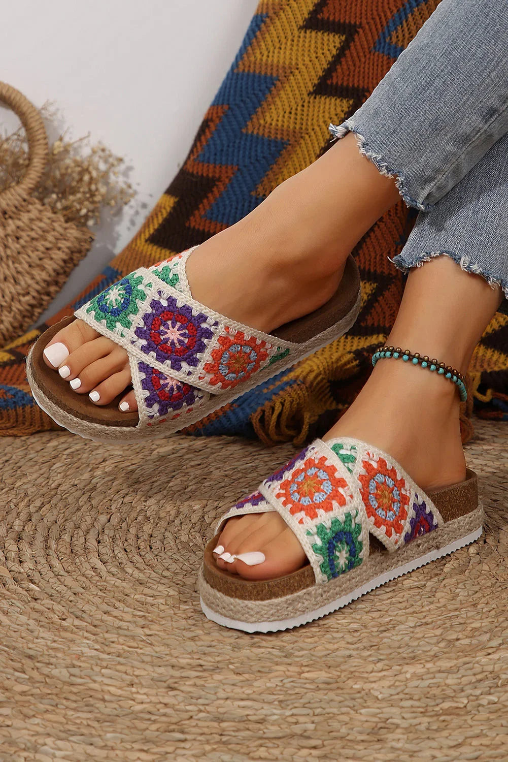 Woman wearing colorful crochet platform sandals with frayed jeans on woven rug