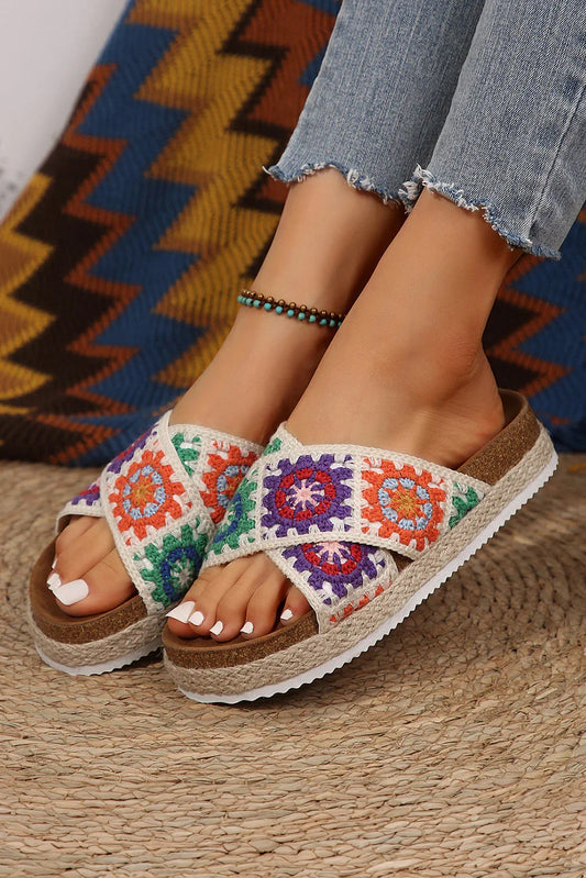 Woman wearing colorful crochet platform sandals with cork sole and blue jeans on woven rug