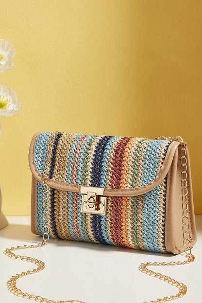 Multicolored woven crossbody bag with gold chain strap and turn-lock closure on beige table.