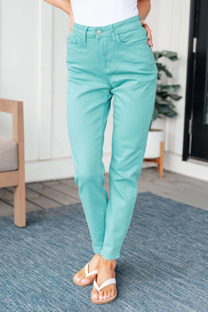 Woman wearing aquamarine high-rise slim jeans with white sandals in a modern setting