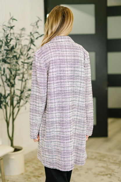 Back view of a woman wearing a lavender and ivory tweed midi blazer indoors