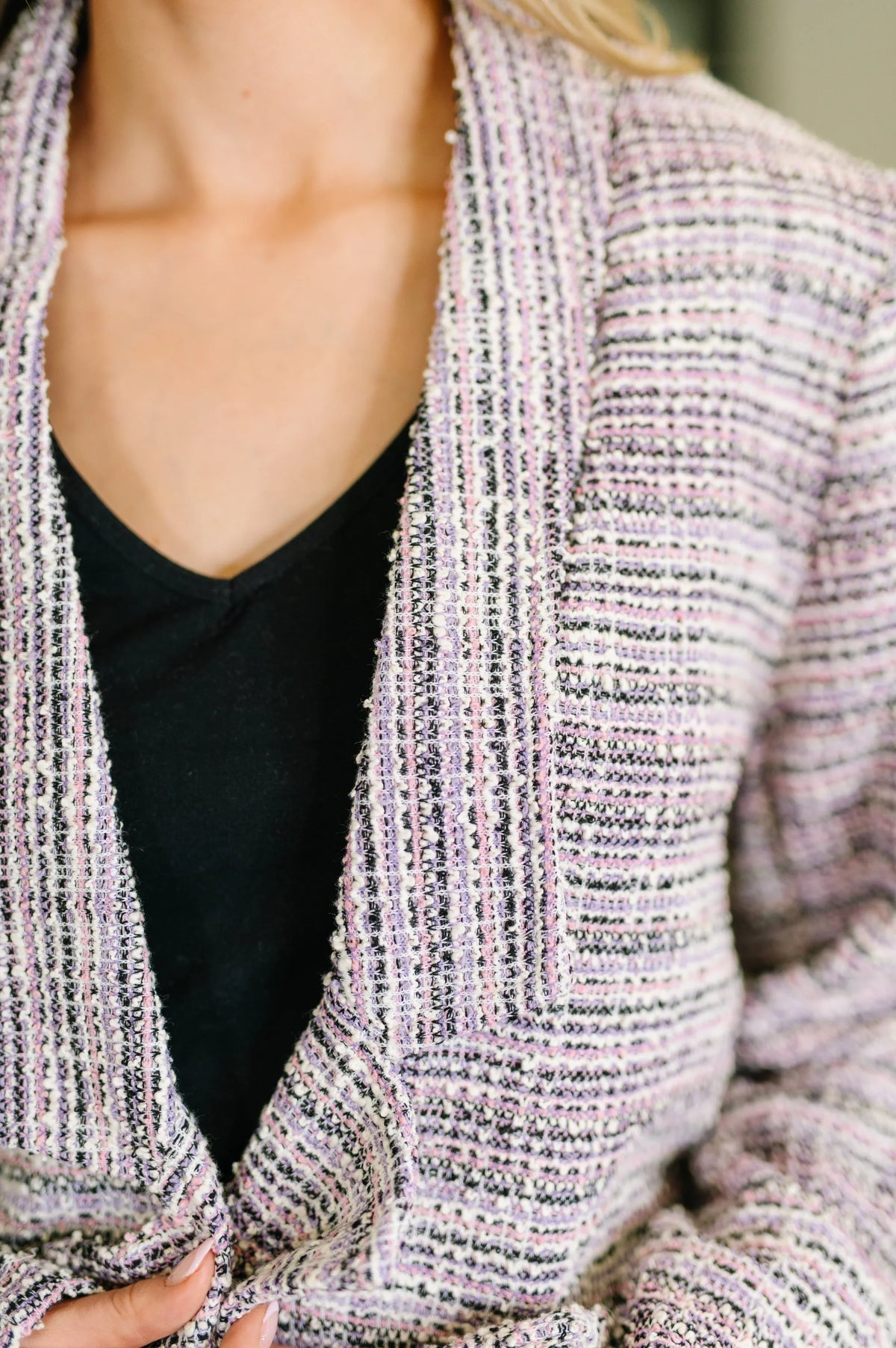 Close-up of a woman wearing a lavender and ivory tweed midi blazer with textured fabric.