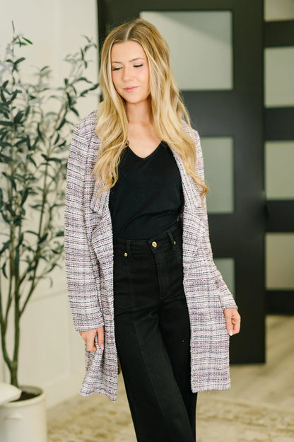 Woman wearing lavender ivory tweed midi blazer over black top and high-waisted black pants