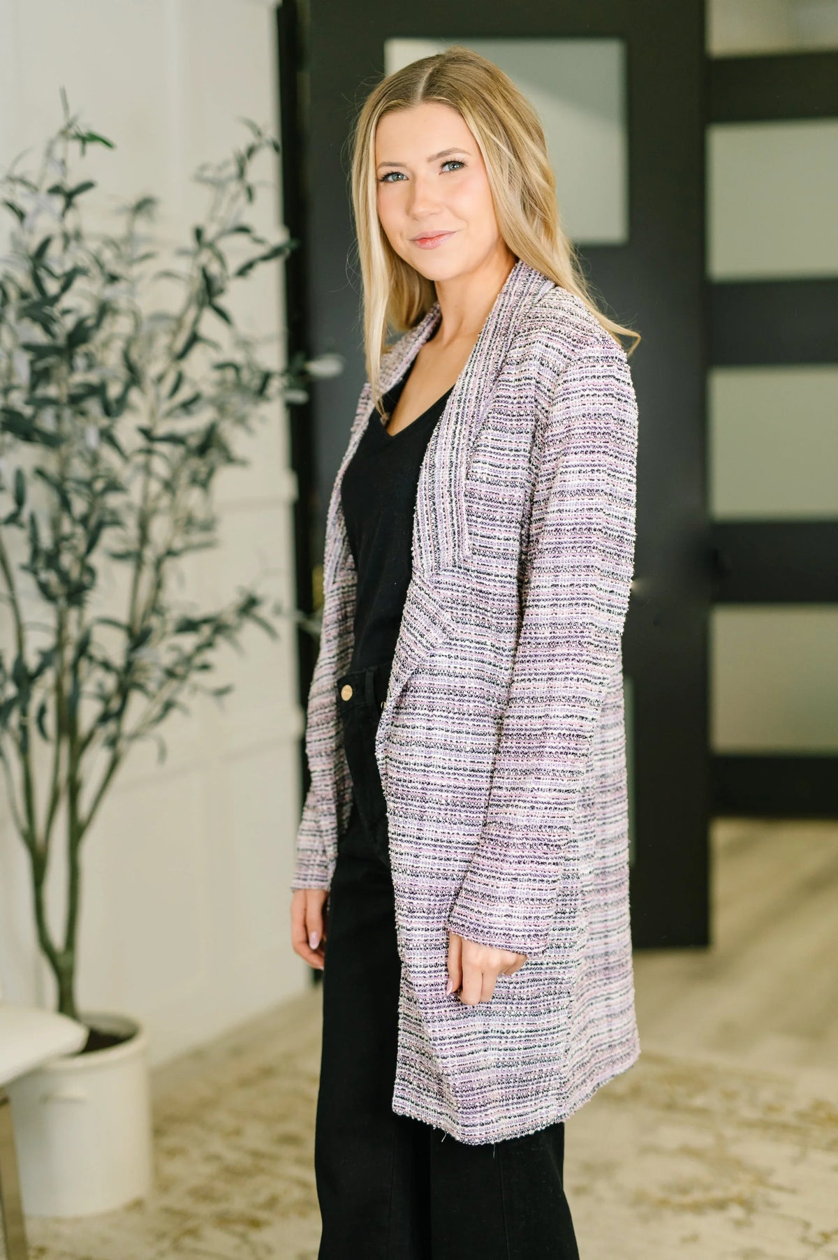 Woman wearing lavender ivory tweed midi blazer over black outfit in modern indoor setting