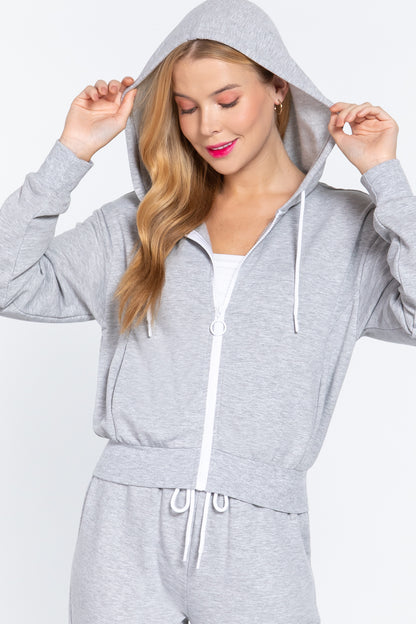 Woman wearing a gray hooded fleece french terry jacket and matching pants on a white background