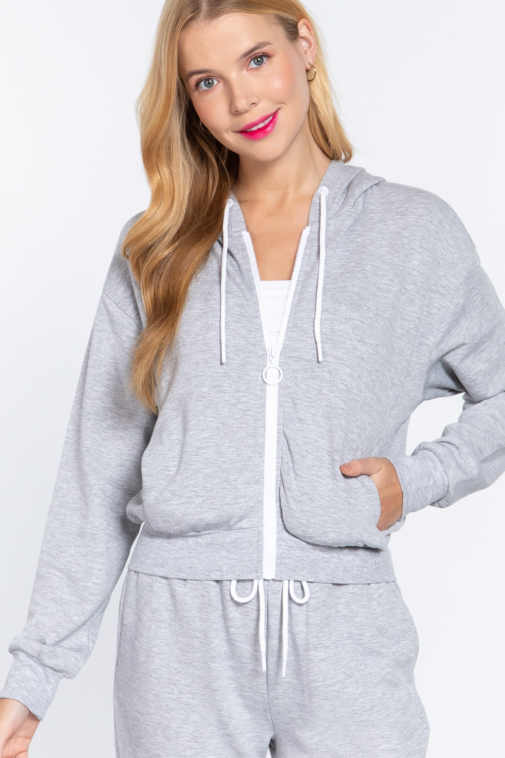 Woman wearing a gray hooded fleece french terry jacket and matching pants on a white background