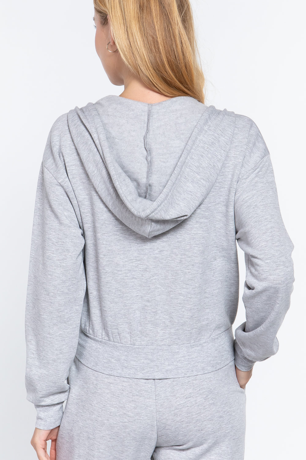 the back of a woman wearing a gray hooded fleece french terry jacket and matching pants on a white background
