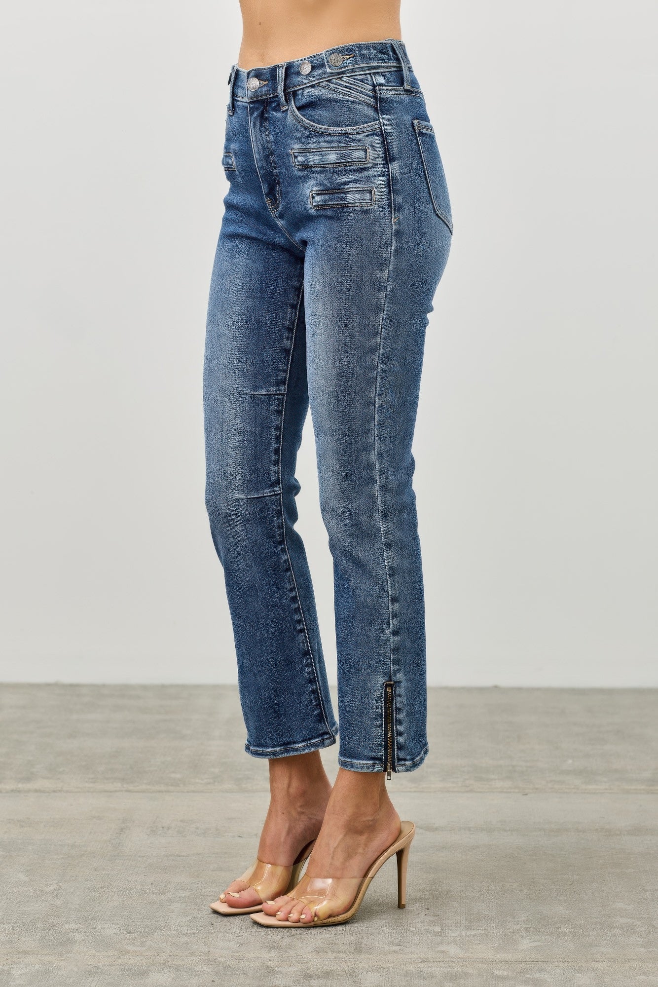 cropped Blue jeans with ankle zipper worn by a woman on a plain background