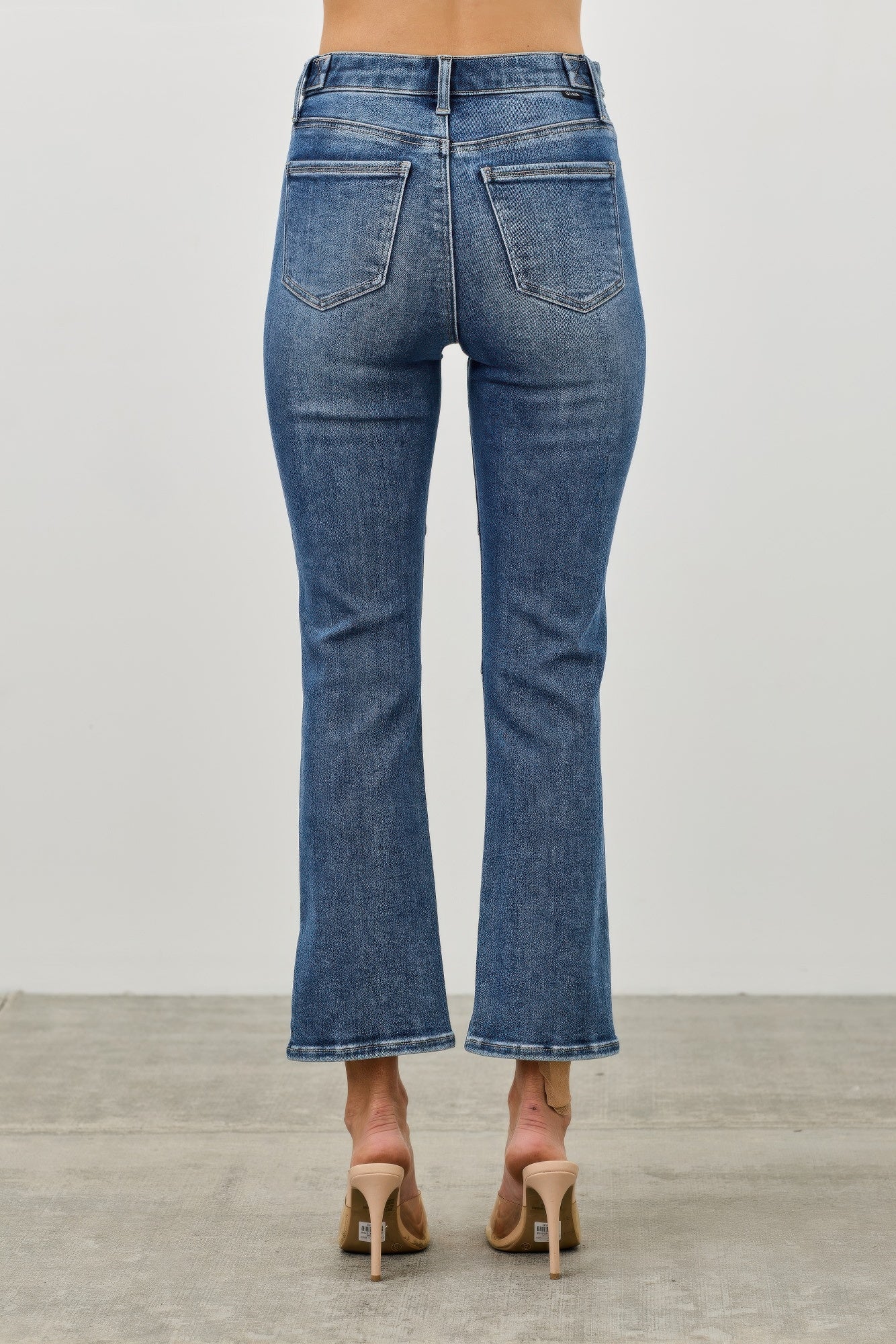 cropped Blue jeans with ankle zipper worn by a woman on a plain background