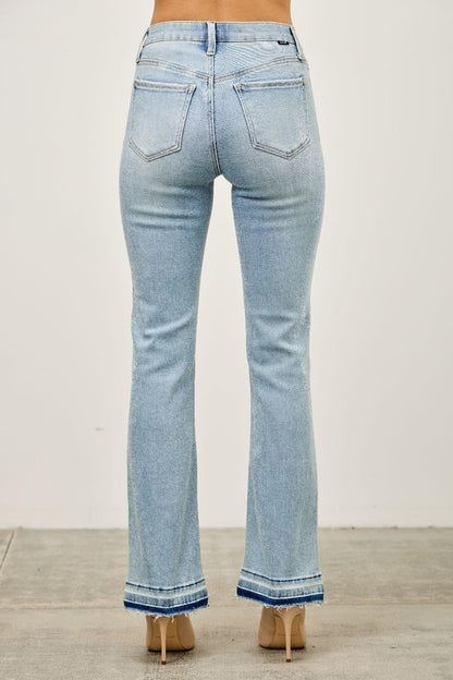 Back view of light wash flare jeans with frayed raw hem and dual back pockets, worn by model